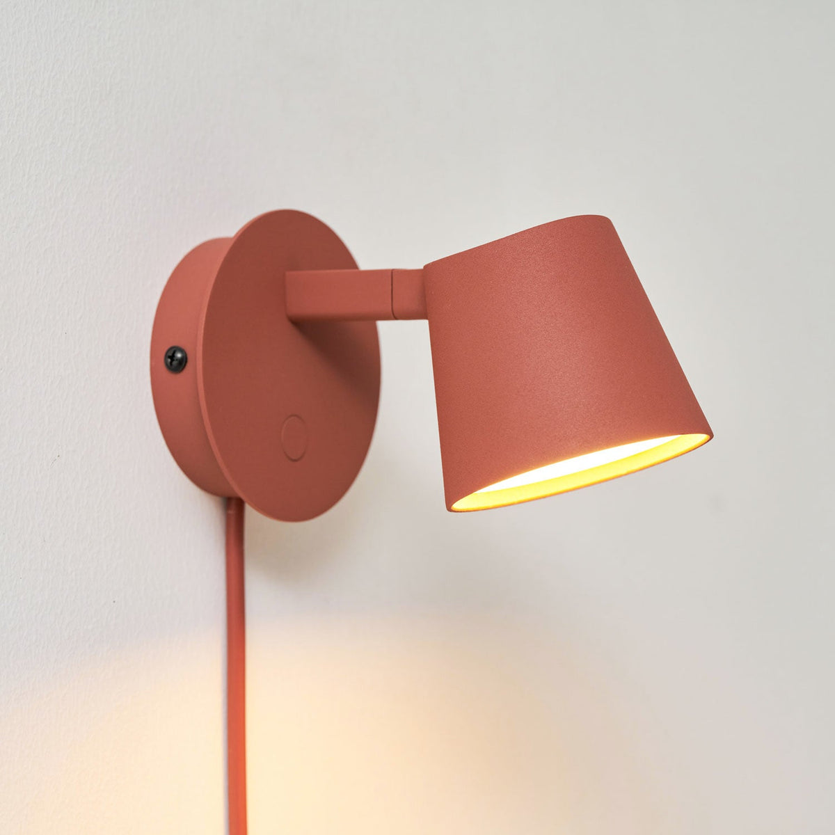 Red Clérachic wall light from the front at an angle, the warm glow lighting the inside of the shade.