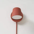 Red Clérachic wall light seen from the front, the cone shade turned down over the round backplate with a white diffuser.