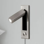 This Clérachic wall light in nickel has its square head swung out, with a round push button below, against a grey wall.
