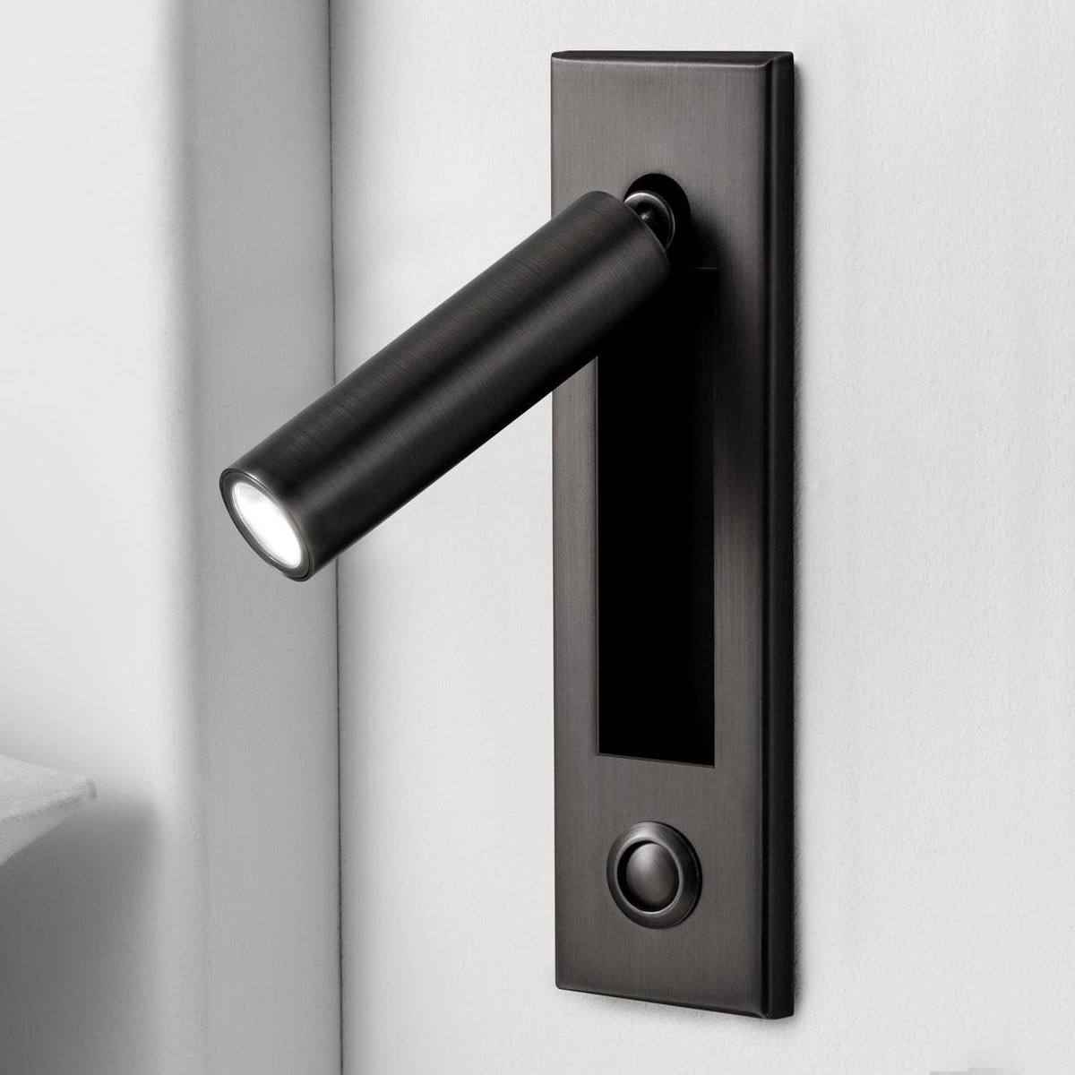 Matt black round head of this Clérachic wall light, angled out from a dark plate with a round button below.