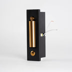 Angled view of the black back box of this Clérachic wall light, with a brass-coloured head, button and wires showing.