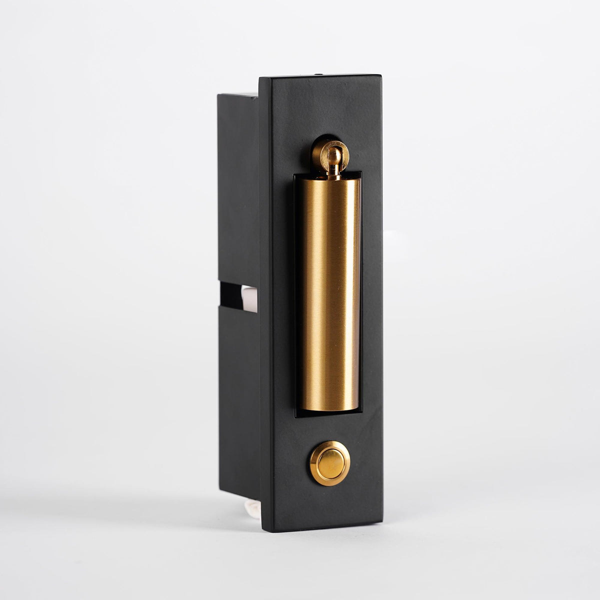 Side view of this Clérachic wall light, its brass-coloured head folded in and a round button on the black plate.