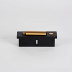 Top view of this Clérachic wall light lying flat, showing its brass-coloured head, round button and black back box.