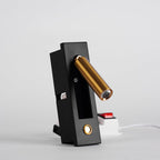 Angled view of this Clérachic wall light with the brass-coloured head swung out, a round button below and a red switch behind.