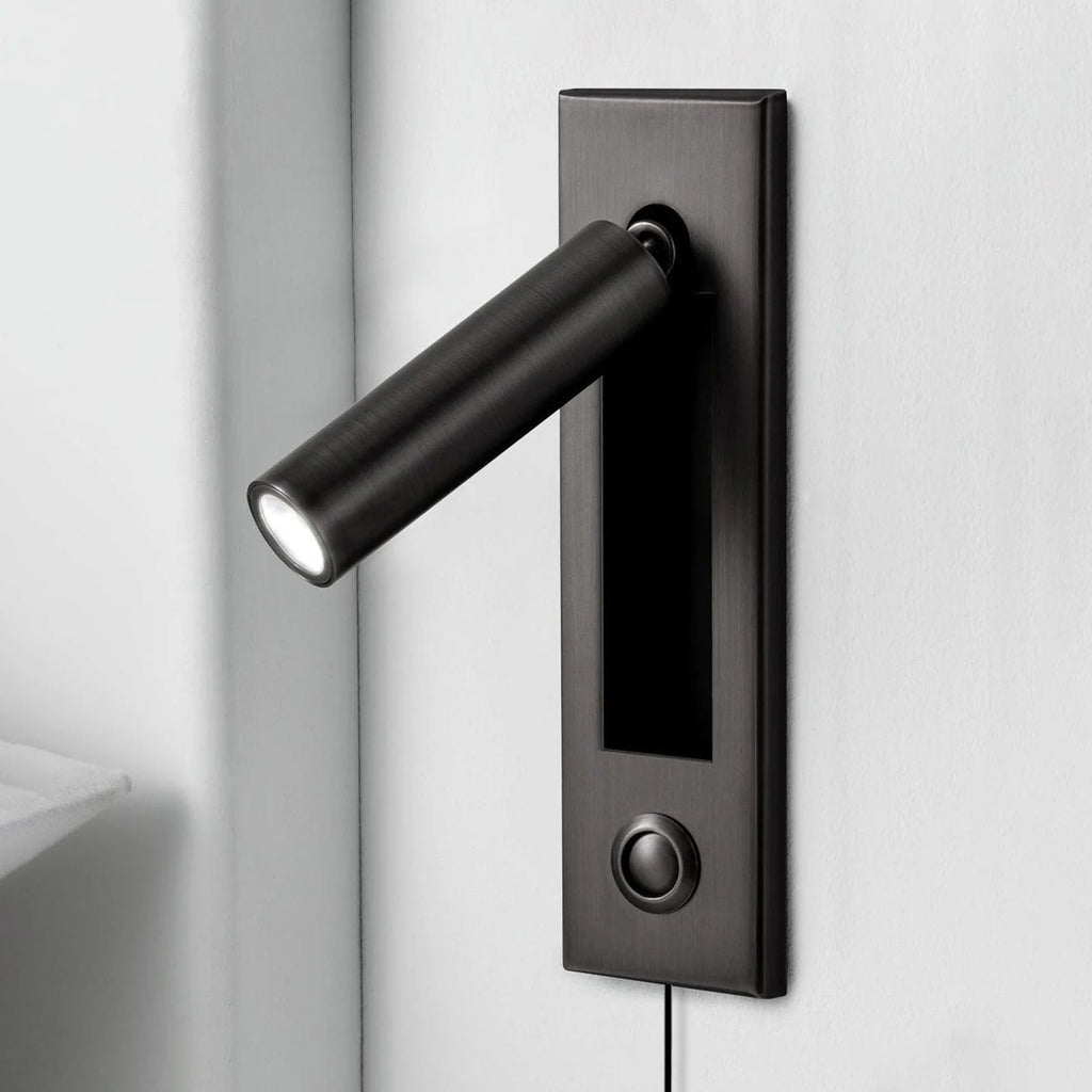 Black round head of this Clérachic wall light angled out from a dark plate, with a push button and a cable below.