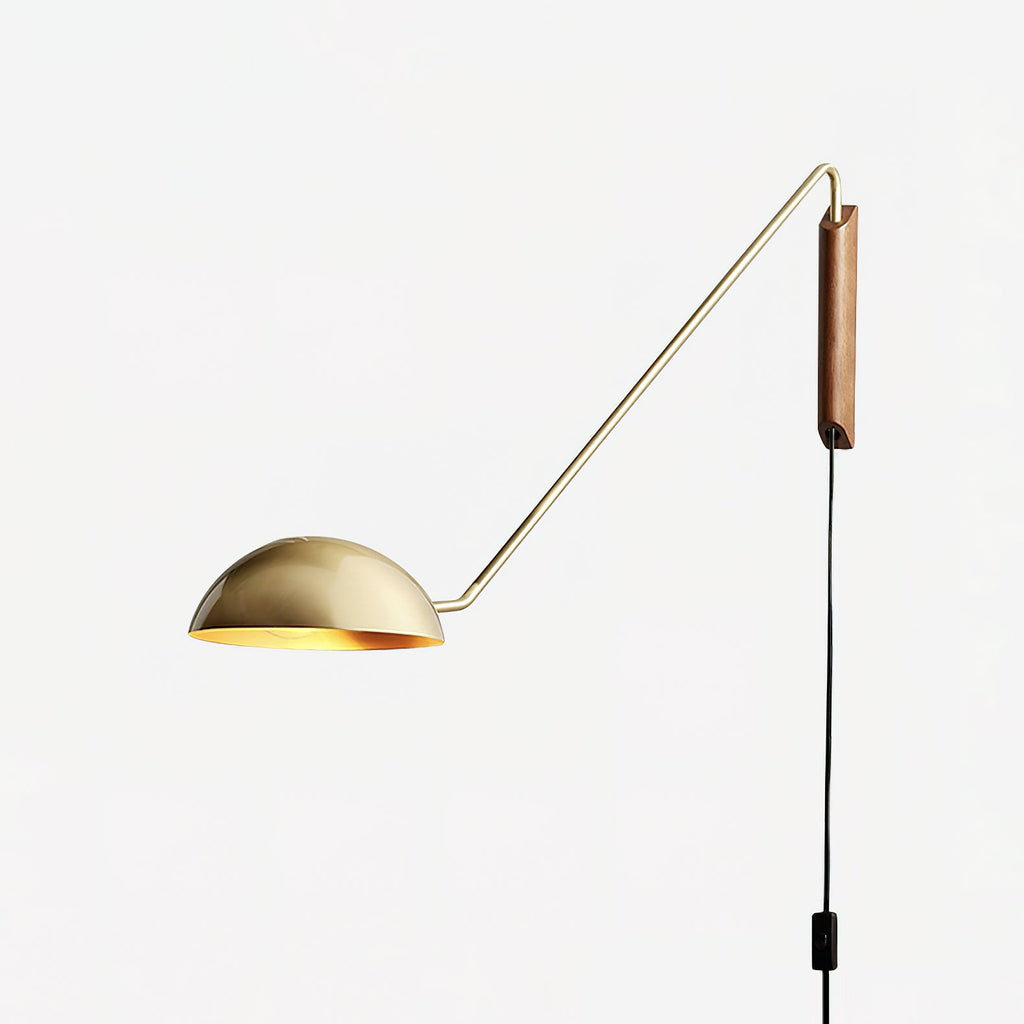 A gold and walnut Clérachic wall light with a thin arm and a half-dome shade, on a plain white backdrop.