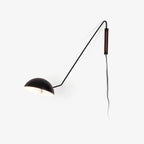 Black Clérachic wall light with a walnut plate and a white inner shade, with its cord trailing, on a plain white background.