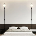 A pair of Clérachic wall lights with single globes on black rods, hung either side of a low bed with grey linen.