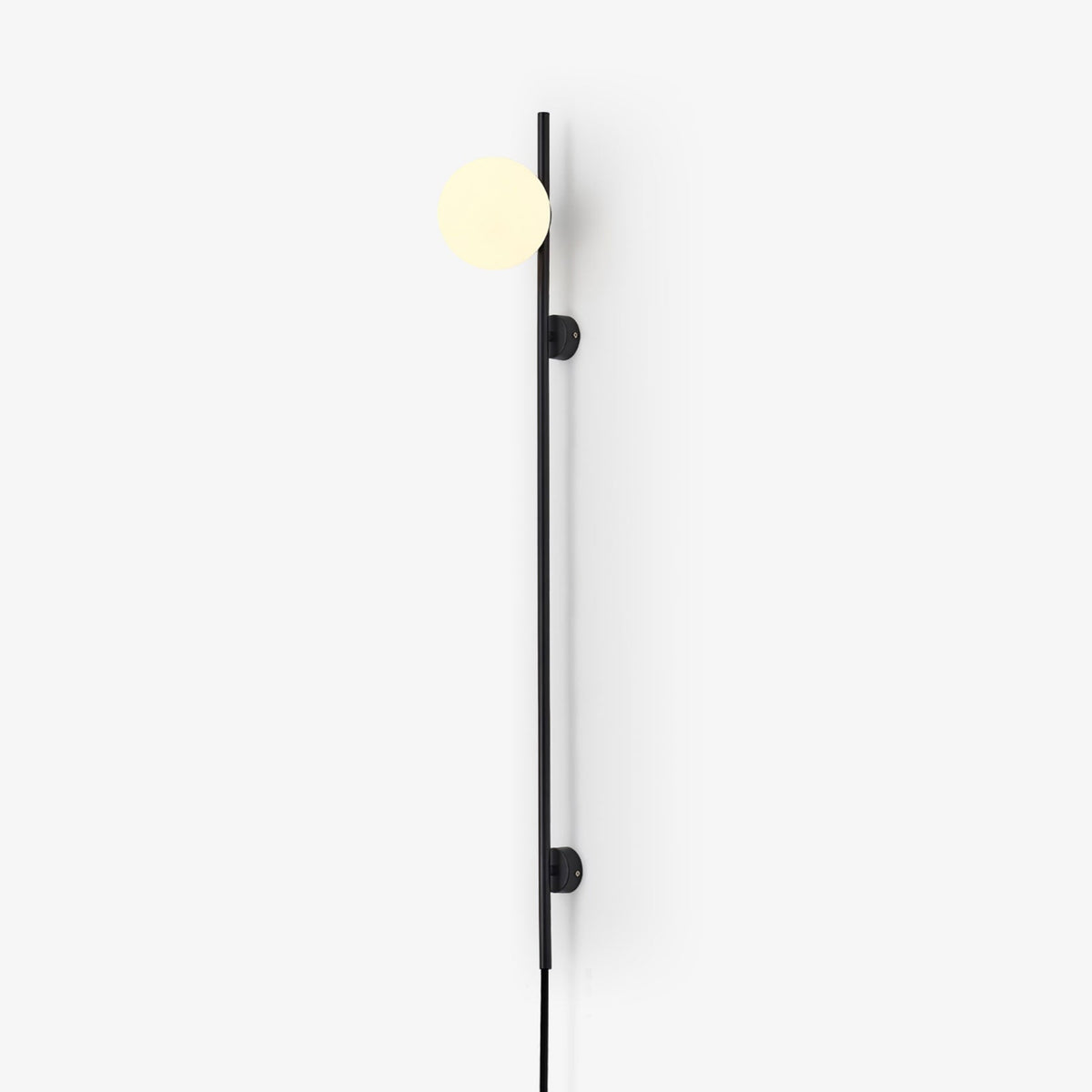 A Clérachic plug-in wall light with a softly lit globe on a thin black rod, with two small mounts, against a bright white wall.
