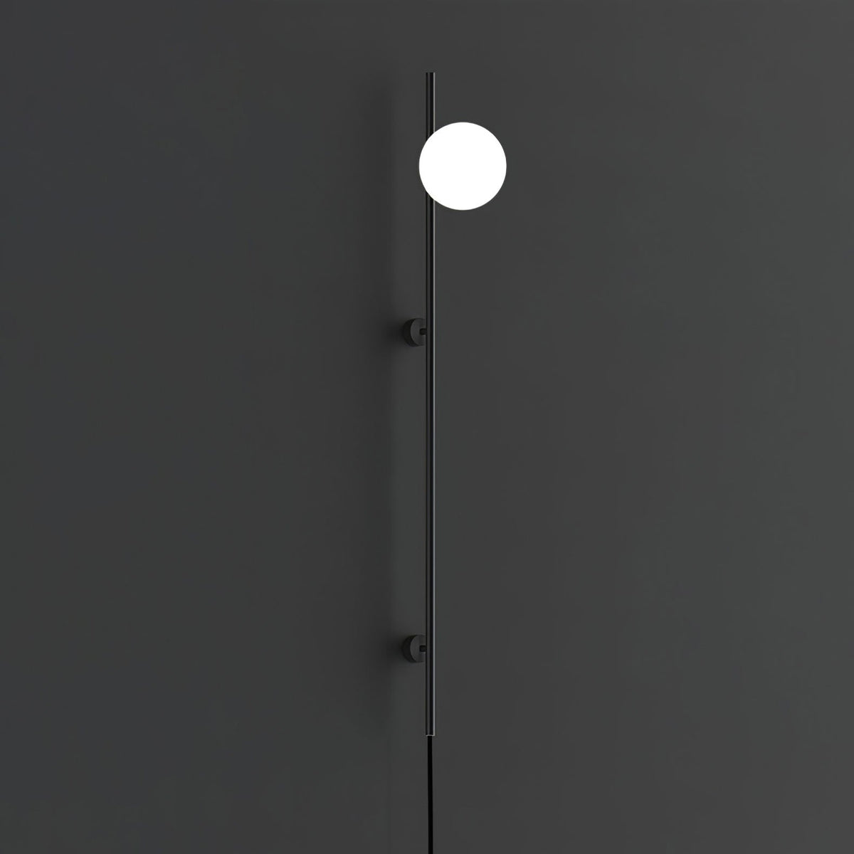 A single bright globe on the slim black rod of this Clérachic wall light, against a dark charcoal wall with two small mounts.