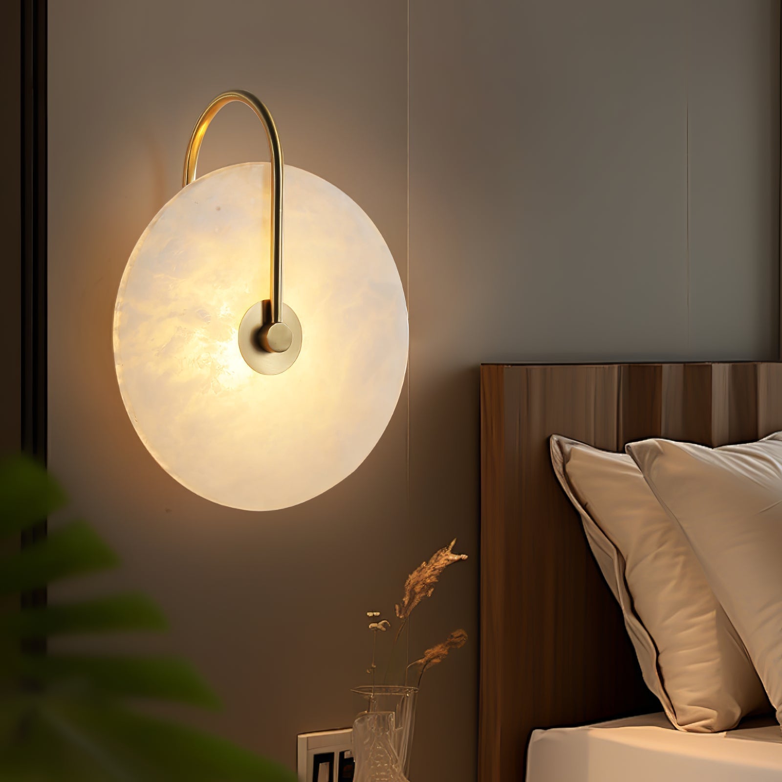 Clérachic Plug-In Wall Sconce glows beside a fluted wood headboard, gold arm over the alabaster globe shade in a bedroom.