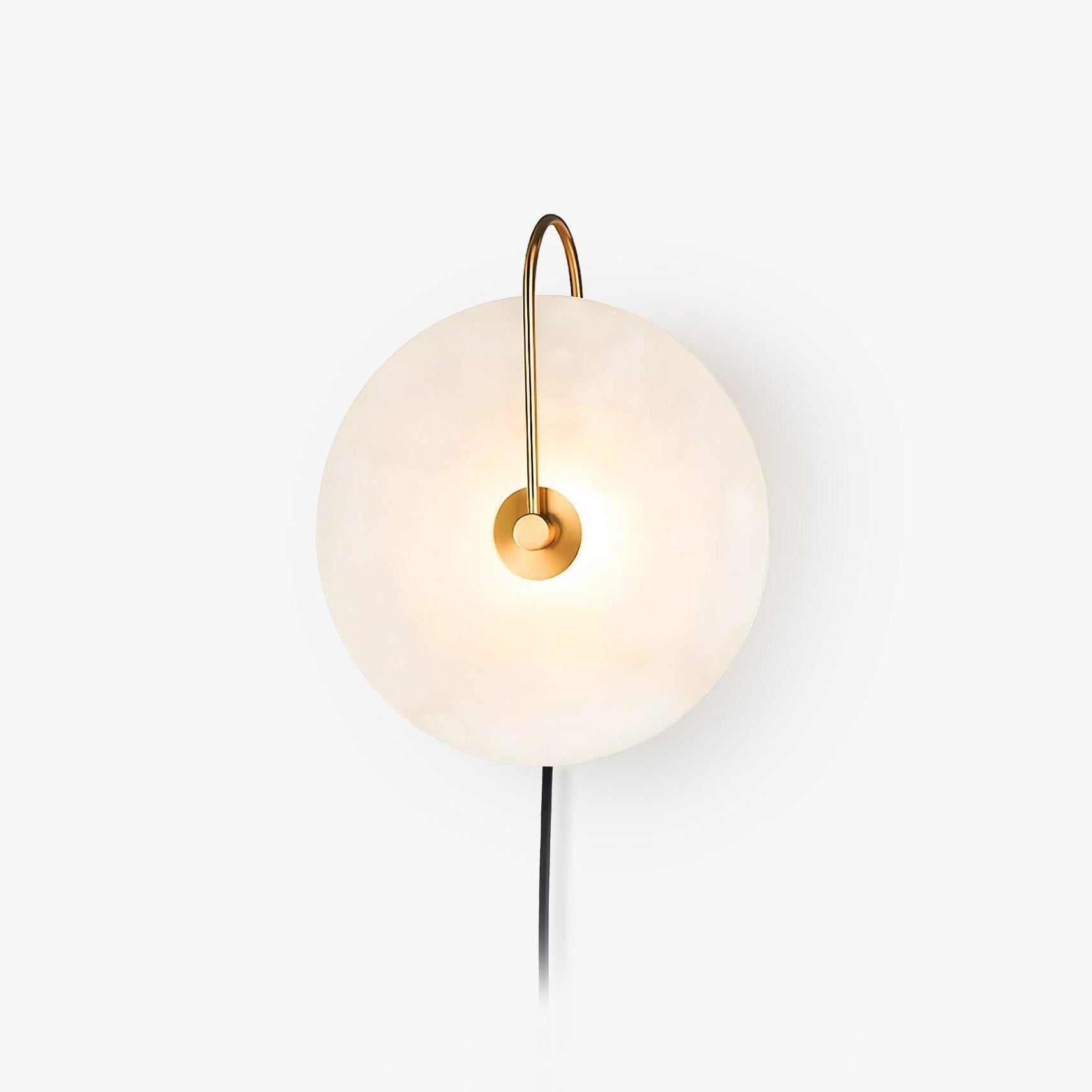 Studio shot of the Clérachic Plug-In Wall Sconce on white, gold arm lit and a black cord trailing from the alabaster disc.