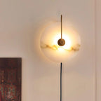 Clérachic Plug-In Wall Sconce lit in a warm room, grey and tan veining showing through the alabaster globe shade.