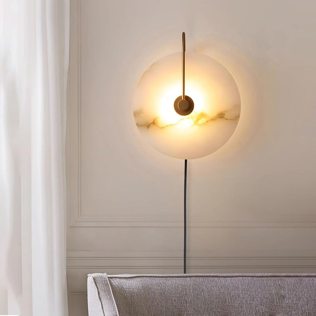 The Clérachic Plug-In Wall Sconce glowing above a grey sofa on a paneled wall, black cord running toward the skirting.