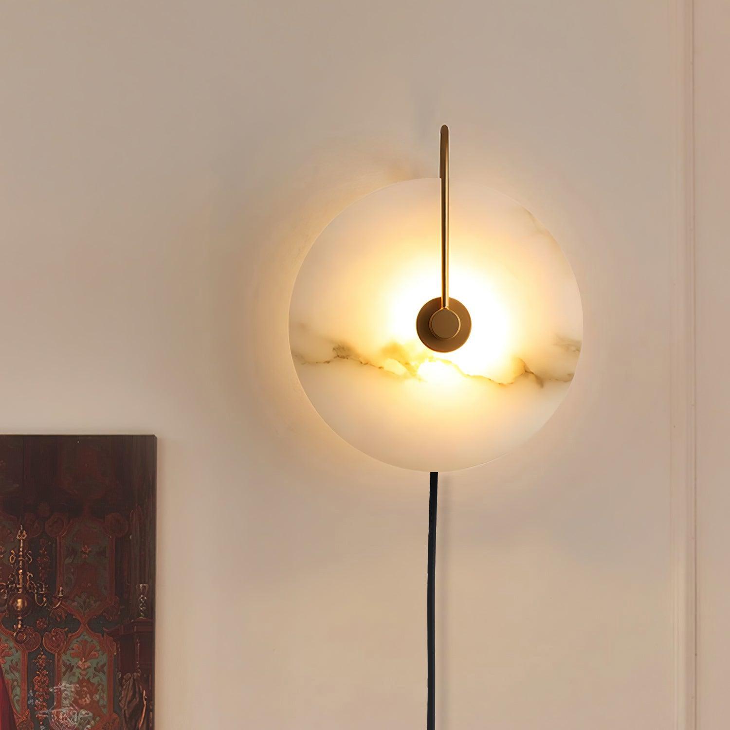 Clérachic Plug-In Wall Sconce with dark veining across the lit alabaster disc, a warm halo cast on the cream wall.