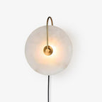 Front view of the Clérachic Plug-In Wall Sconce on a white studio backdrop, glow centred behind the gold hub.