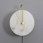 Clérachic Plug-In Wall Sconce switched off on a grey wall, warm brown veining running through the alabaster globe shade.
