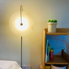 Clérachic Plug-In Wall Sconce lit beside a bed, black cord running down to wall outlets by a light-wood bookshelf.