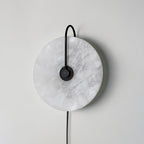 Clérachic Plug-In Wall Sconce in the black finish, switched off, with grey veining across the unlit stone disc.