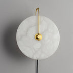Frontal studio view of the Clérachic Plug-In Wall Sconce on matte grey, gold hook arm and black cord under a warm disc.