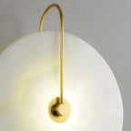 Close-up of the Clérachic Plug-In Wall Sconce from the side, gold rod and cloudy alabaster glowing on textured plaster.