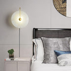 Clérachic Plug-In Wall Sconce lighting a paneled bedroom above a grey nightstand, gold arm beside a woven mesh headboard.