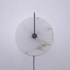 Unlit black-finish Clérachic Plug-In Wall Sconce on grey, beige and brown veining across the pale alabaster globe shade.