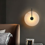 Black-arm Clérachic Plug-In Wall Sconce glowing on a charcoal bedroom wall beside a brown leather headboard.