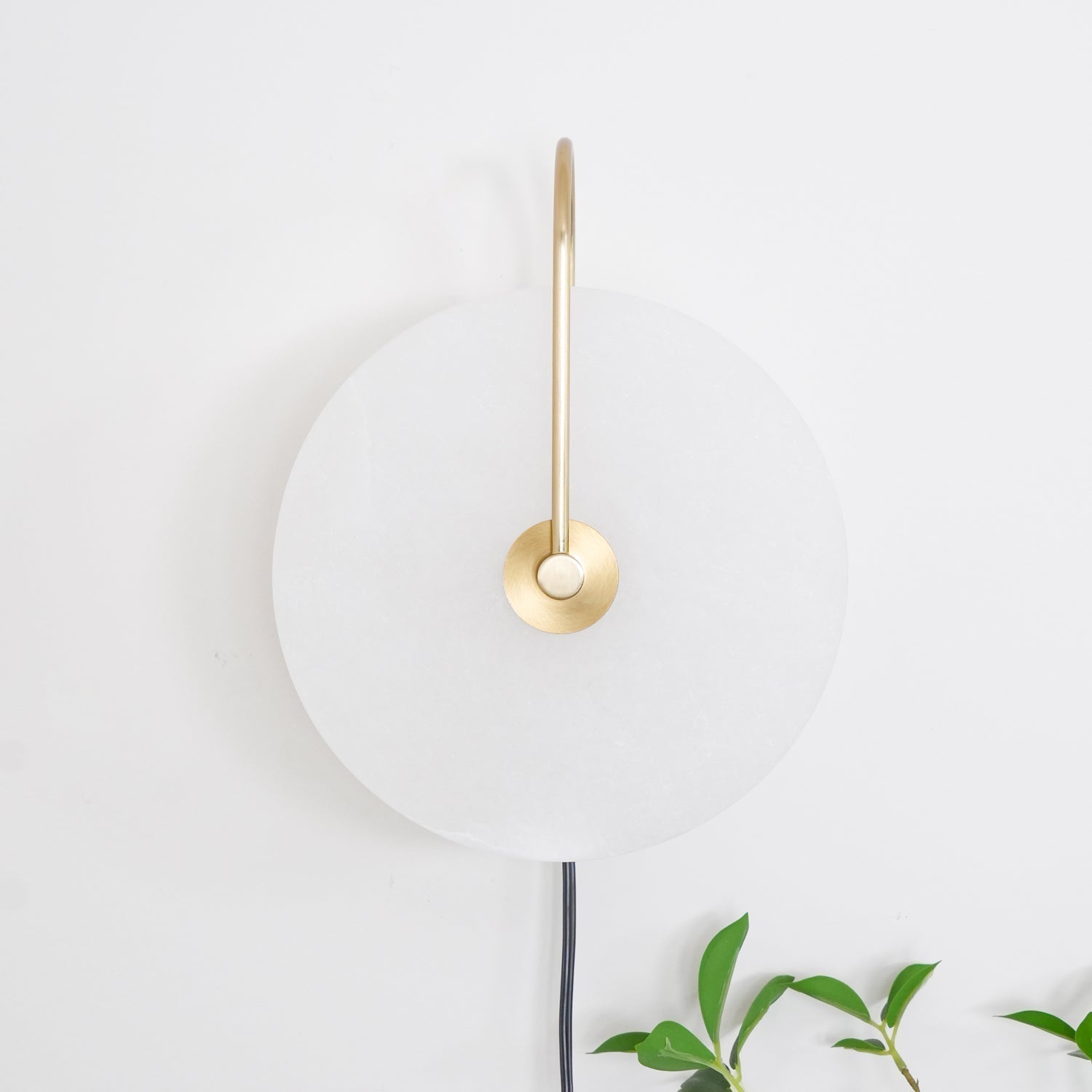 Bright, even view of the Clérachic Plug-In Wall Sconce unlit, gold arm and black cord with green leaves at the corner.