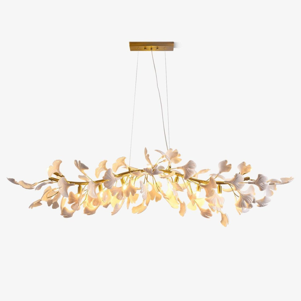 Clérachic linear chandelier hung from a gold rectangular canopy, its length covered in white porcelain ginkgo leaves, lit on a plain pale backdrop.