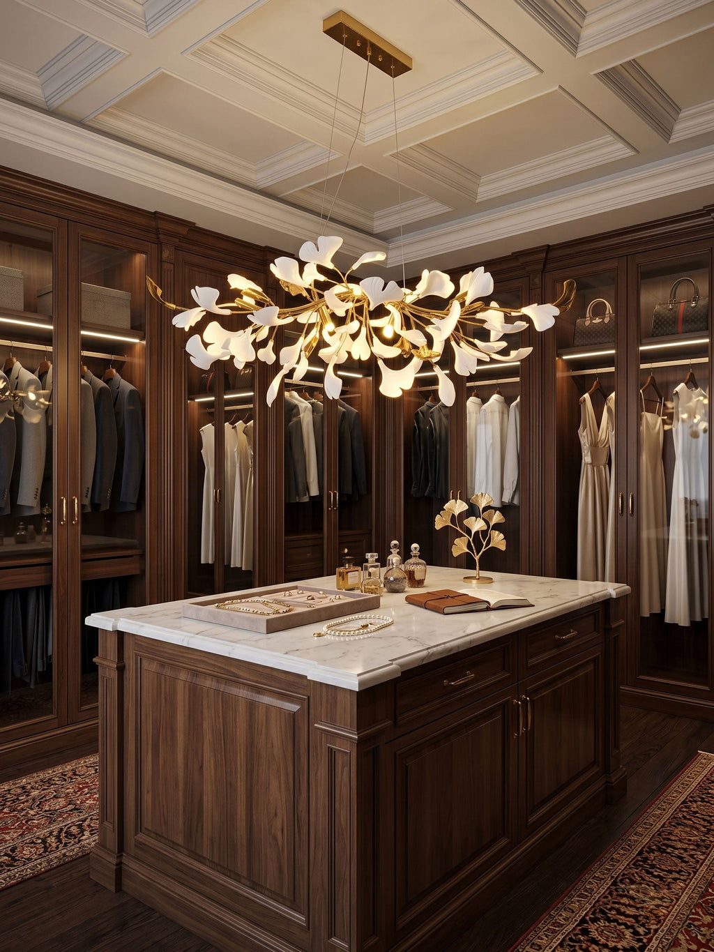 A Clérachic ginkgo-leaf chandelier above a marble-topped island in a walnut dressing room, with glass-fronted wardrobes lining the walls.