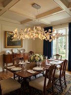 Clérachic chandelier glowing above a dark wood dining table in a coffered-ceiling room, with navy curtains at the tall window.