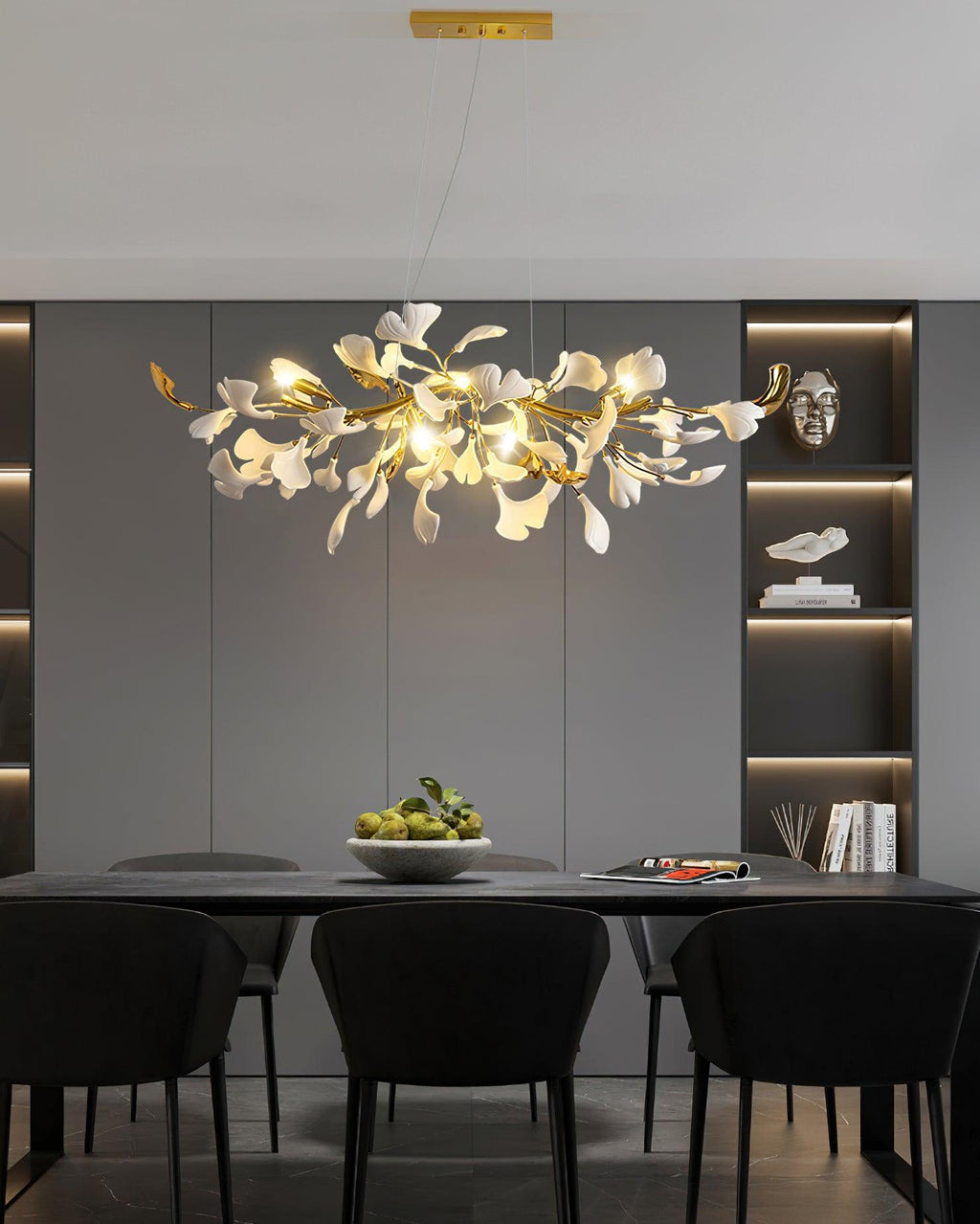 Clérachic chandelier lit over a black dining table in a dark grey room with backlit shelving and black upholstered chairs.