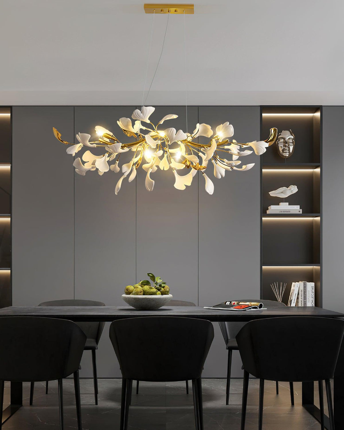Clérachic chandelier lit over a black dining table in a dark grey room with backlit shelving and black upholstered chairs.