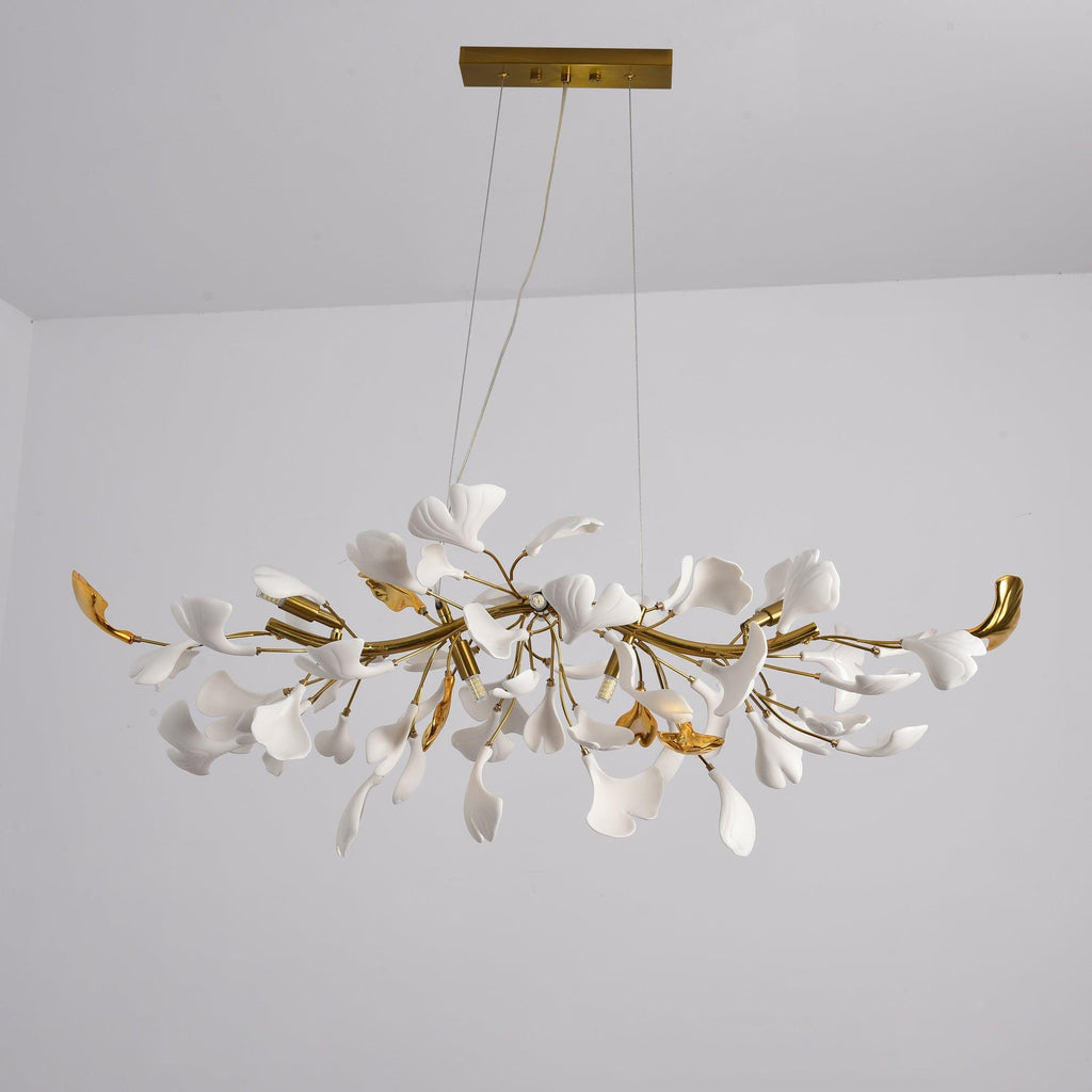 Unlit Clérachic chandelier, white leaves among gold branches with curved gold tips, hanging from two cables under a gold canopy.