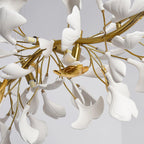 Close view of gold branches, white porcelain leaves and a small gold bird-shaped detail inside this Clérachic chandelier.