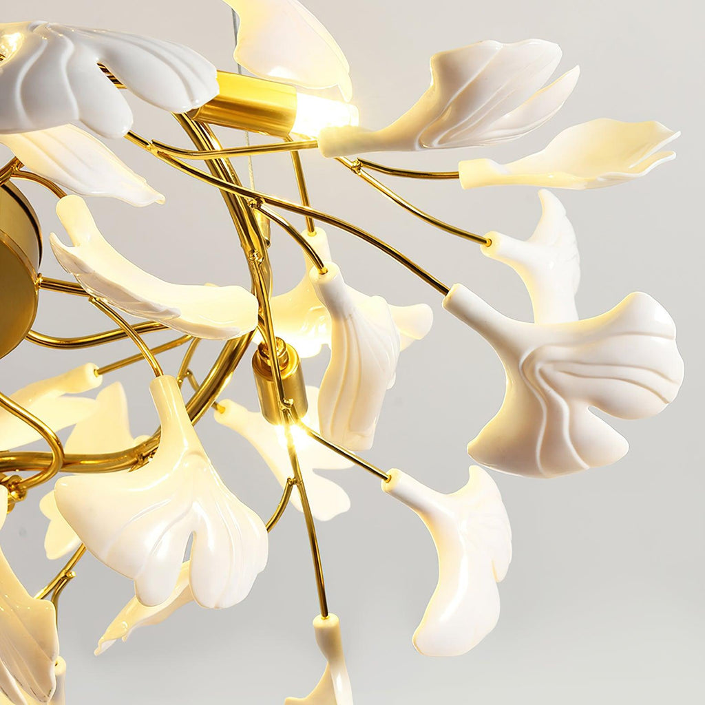 Close view of glowing white ginkgo leaves with ribbed surfaces around a lit gold bulb holder on this Clérachic chandelier.