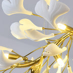 Close view of lit LED capsules in gold holders among white leaves on this Clérachic chandelier, thin hanging cable behind.