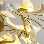 Detail of a lit bulb holder and the curved gold central frame of this Clérachic chandelier, white leaves wrapped around it.