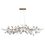 Clérachic chandelier with white leaves on a gold branch, hanging from two cables under a gold canopy, on a plain white backdrop.