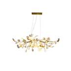 Clérachic chandelier with lit white leaves and gold curved ends, shown whole beneath a gold canopy on a white backdrop.