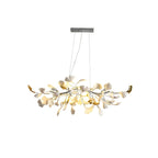 Lit Clérachic chandelier with a silver-toned canopy and branch, its white and gold-tinged leaves glowing on a plain white backdrop.