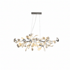Clérachic chandelier with a nickel-toned canopy and branch, silver and white leaves lit, on a plain white backdrop.