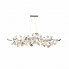 Clérachic chandelier with white and silver leaves along a nickel branch, softly lit, on a plain white backdrop.