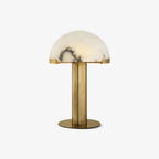 Clérachic alabaster table lamp with a gold stem and base, its white veined dome seated on a plain light backdrop.