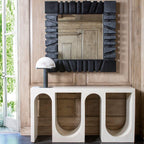 Small Clérachic table lamp with a dark base on a white arched console, below a mirror in a heavy black frame on a timber-panelled wall.