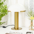 Gold Clérachic table lamp shown from slightly closer, its wide white dome filling the top of the frame above a round brass base.