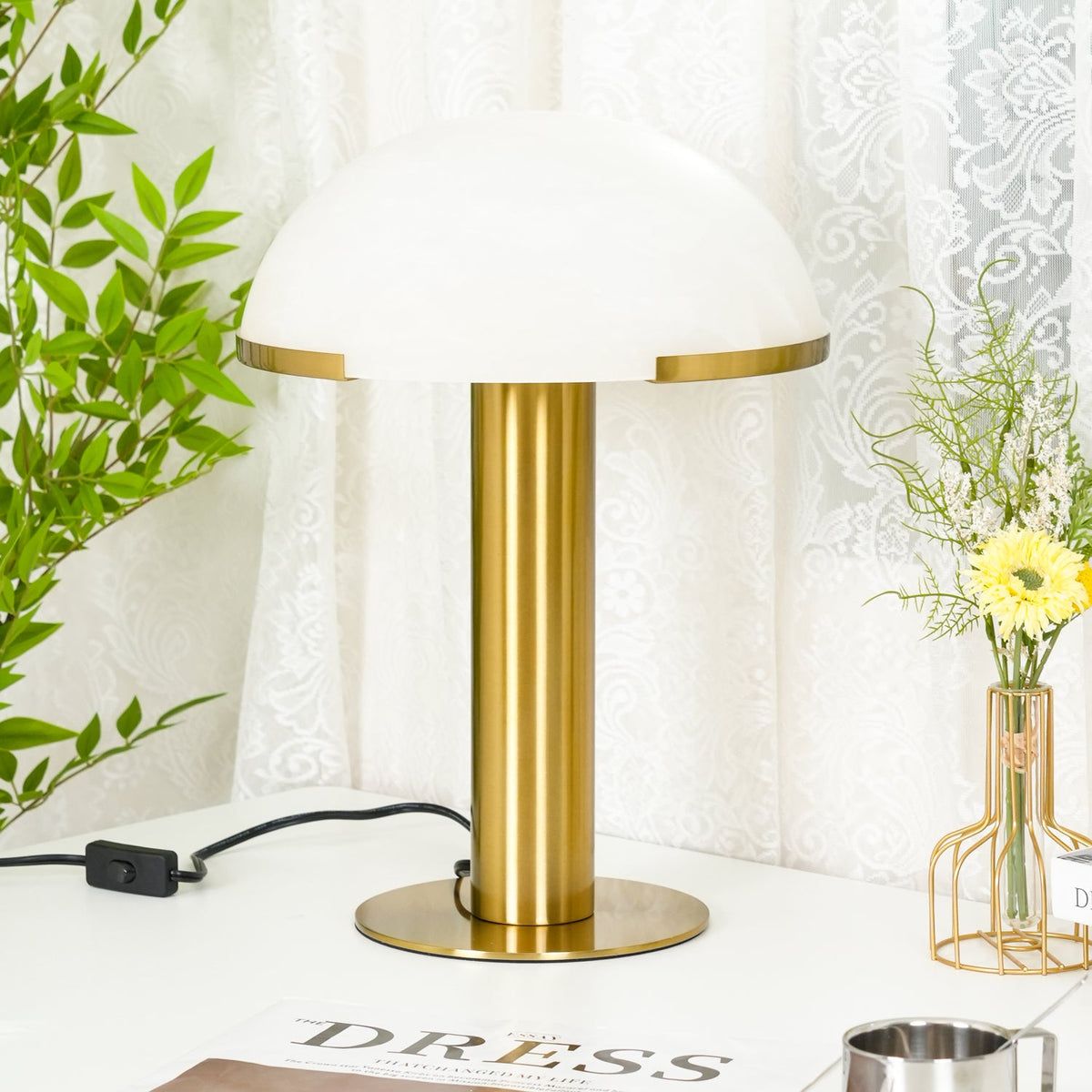 Gold Clérachic table lamp shown from slightly closer, its wide white dome filling the top of the frame above a round brass base.