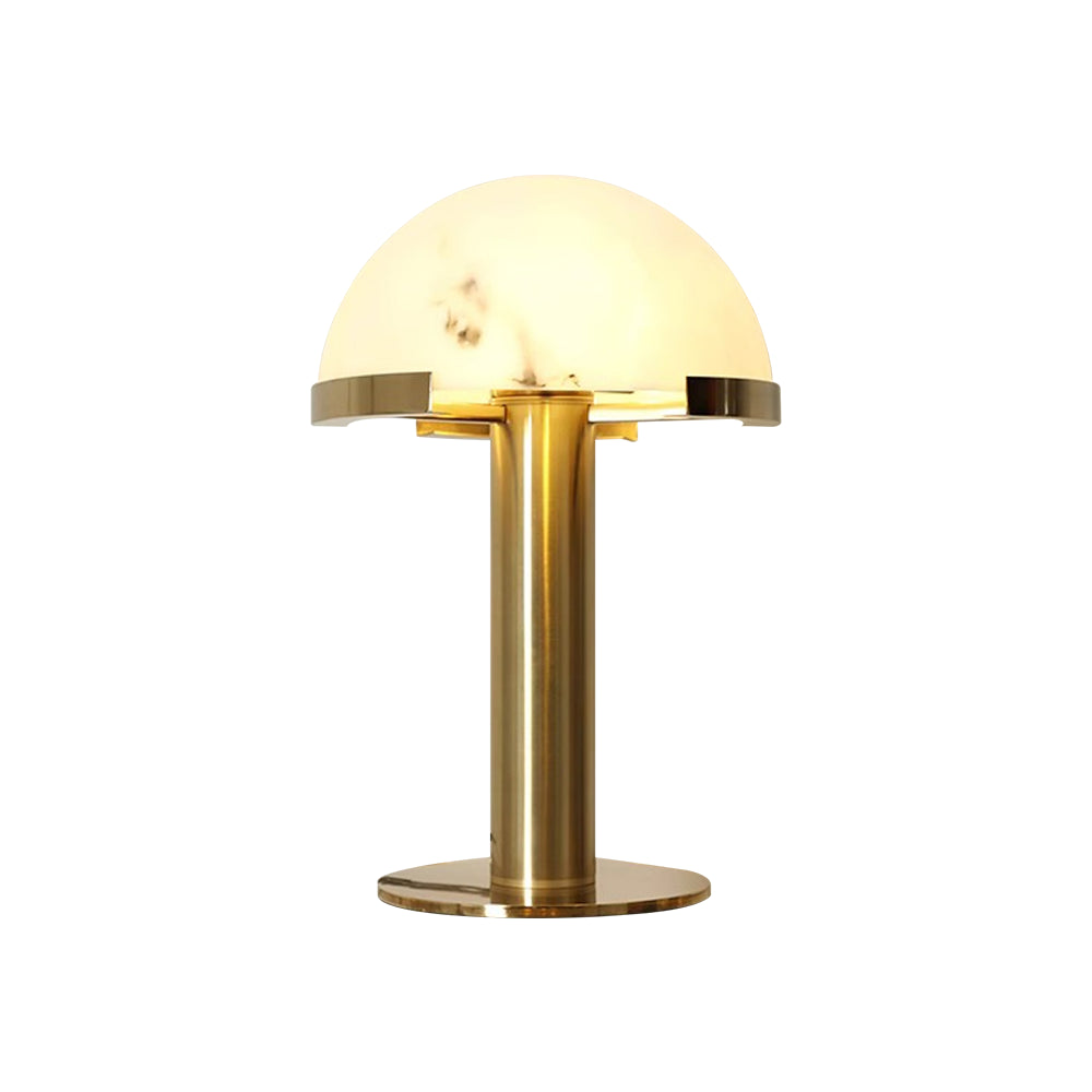 Gold Clérachic table lamp lit from within on a plain white background, the brass base ring catching the light.
