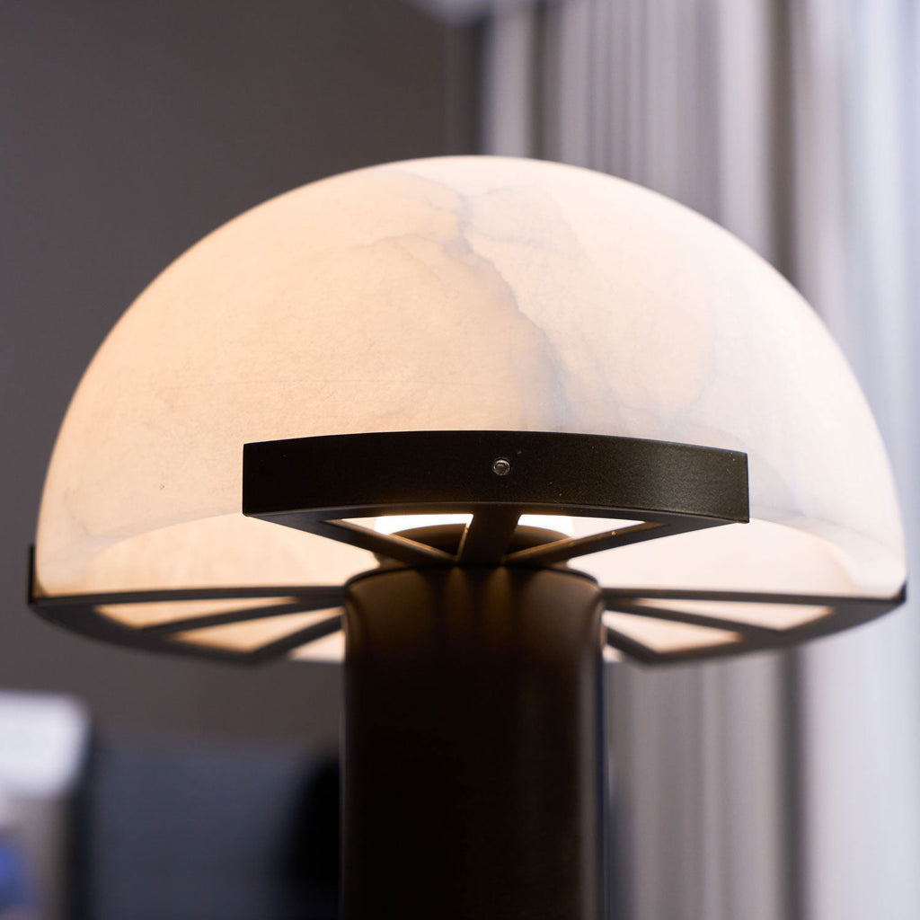 Underside close view of this Clérachic table lamp, showing the black support ring and spokes beneath the glowing alabaster dome.